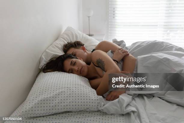 couple of women sleeping together and embracing - lesbian bed stock pictures, royalty-free photos & images