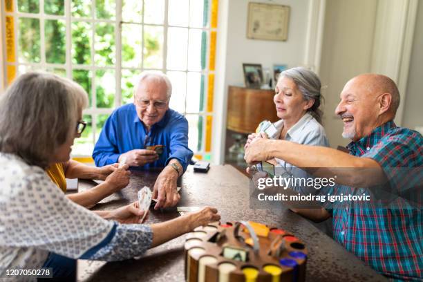 senior friends playing poker at home - senior men playing cards stock pictures, royalty-free photos & images