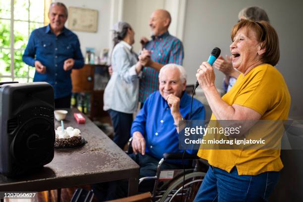 senioren mit spaß bei karaoke-party - senior man dancing on table stock-fotos und bilder