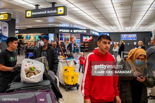 Passengers landing from Brussels arrive in the International arrivals zone at Dulles airport outside Washington on March 13, 2020. - US President...