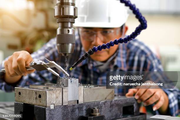 hands of skill mechanic worker working on lathe spare part machine in iron manufacturing factory. man ith helmet, gloves, and uniform plaid shirts amend car spare part. - milling stock pictures, royalty-free photos & images