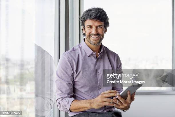 smiling male executive using digital tablet - mid adult stock pictures, royalty-free photos & images