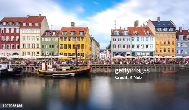 sun beam at beautiful sunset time through boat or ship for water transportation and a lot of tourist at nyhavn, famous colorful building bay front where is a landmark in copenhagen, capital city of denmark, europe, scandinavia - k'nub stock pictures, royalty-free photos & images