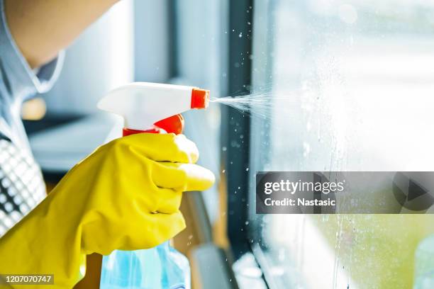 ventana de lavado de mujer joven - botella para rociar fotografías e imágenes de stock