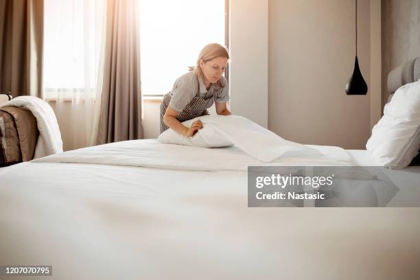 meid die het bed in een hotel maakt - bed linen stockfoto's en -beelden