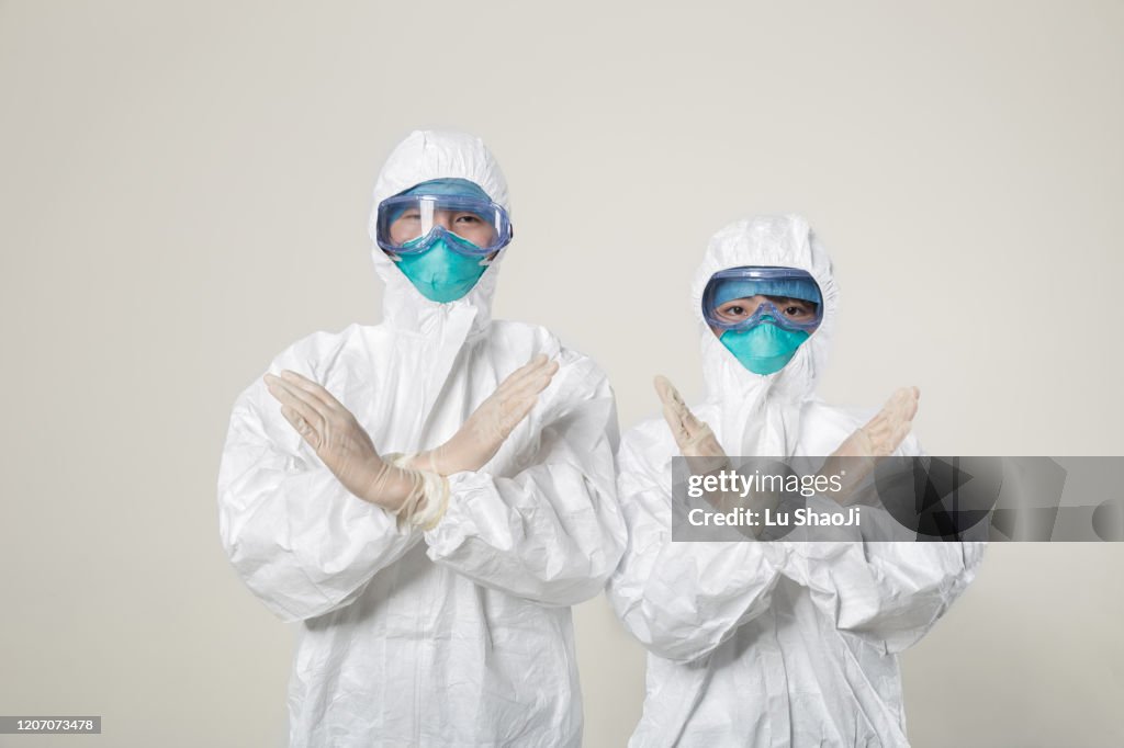 CDC staff standing in front of the white background wall with rejection gesture.