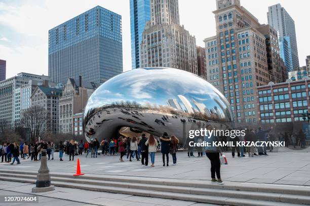 People visit Cloud Gate statue, known as the "Bean", in Millennium Park in Chicago, Illinois, on March 13, 2020. - US President Donald Trump declared...