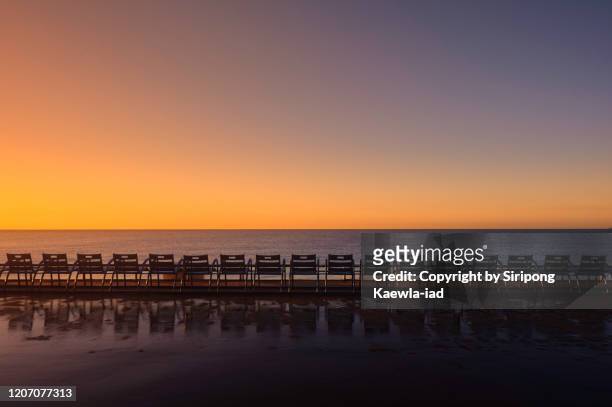 row of outdoor chairs in abreast with its reflection at dawn in nice, provence-alpes-côte d'azur, france. - nice promenade des anglais photos et images de collection