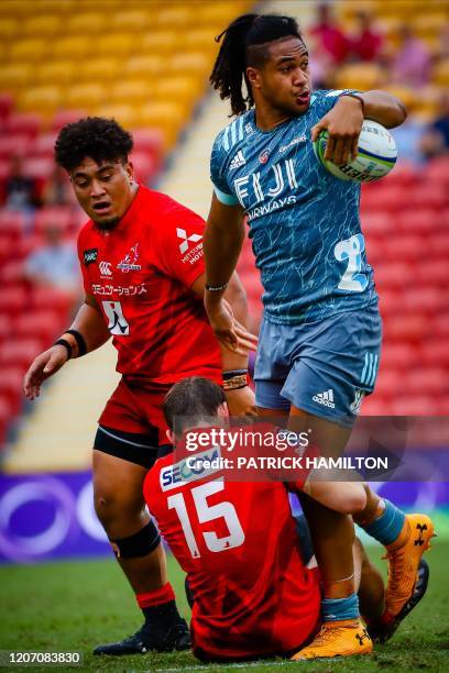 Crusaders' Leicester Faingaanuku breaks the tackle of James Dargaville and Efitusi Maafu of Sunwolves during the Super Rugby match between Japan's...