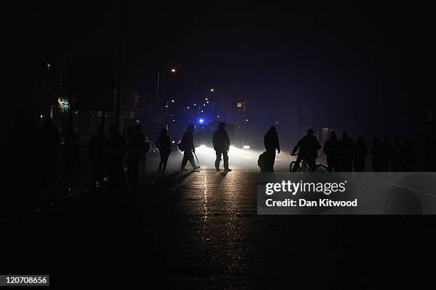 Police officers make their way down a blackened street after a blackout in Croydon on August 8, 2011 in London, England. Sporadic looting and clashes...