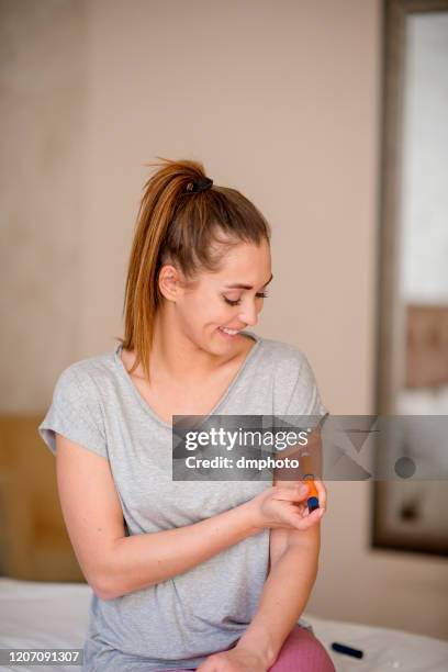 mujer joven inyectando insulina en su brazo - insulina fotografías e imágenes de stock