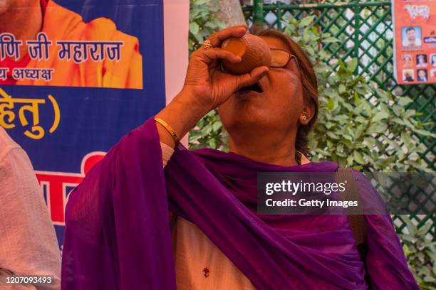 Woman member and supporter 'Akhil Bharat Hindu Mahasabha' a Hindu organisation, drinks cow urine as she attends a 'gaumutra party' to fight against...