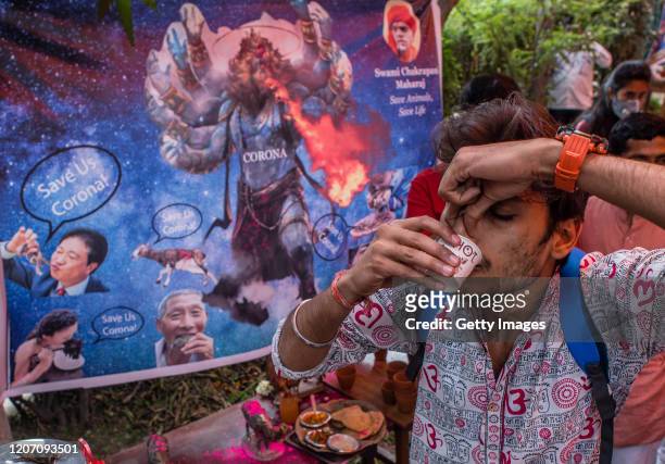 Man participates in a urine drinking party hosted by the Hindu organisation 'Akhil Bharat Hindu Mahasabha' on March 14, 2020 in New Delhi, India....