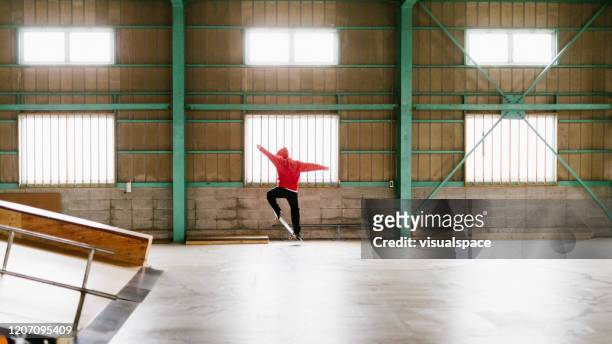 red skateboarder mid-air ollie - indoor skating stock pictures, royalty-free photos & images