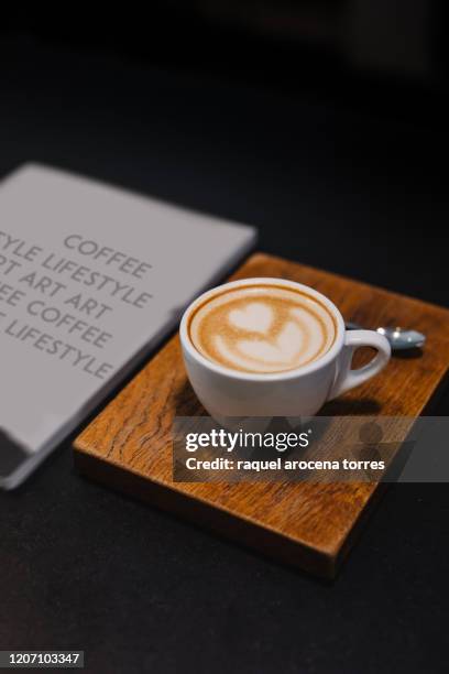 side view of a coffee with a drawing made with milk and a magazine - coffee table books stockfoto's en -beelden