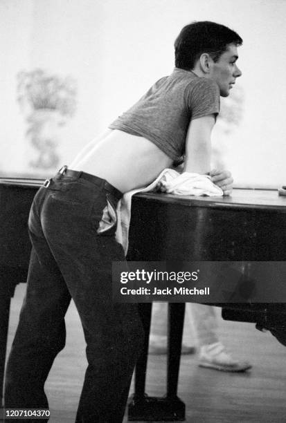 Dancer Dirk Sanders leans against a piano during backstage rehearsals for Mary Martin's Easter Sunday live color telecast , 1959.