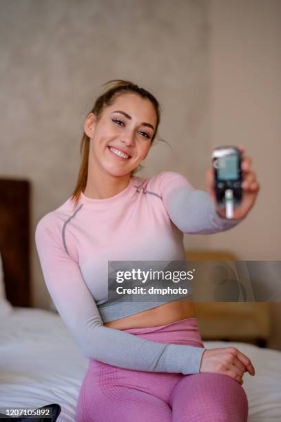 mujer feliz sosteniendo el glucómetro, comprobando el nivel de azúcar - prueba-de-azúcar-en-la-sangre fotografías e imágenes de stock
