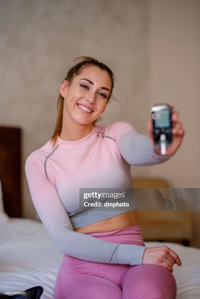 Mulher feliz segurando glucometer, verificando o nível de açúcar