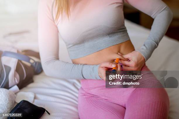 young women injecting insulin after a workout - injecting stomach stock pictures, royalty-free photos & images