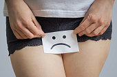 Vaginal or menstrual problems concept. Young woman holds paper with SOS above crotch.