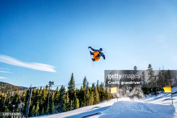 一個年輕的男性滑雪板運動員在陽光明媚的一天在科羅拉多州的滑雪區跳下跳下 - half pipe 個照片及圖片檔
