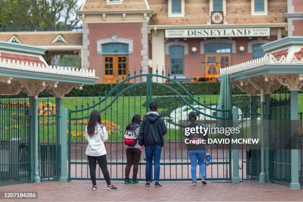 People stand outside the gates of Disneyland Park on the first day of the closure of Disneyland and Disney California Adventure theme parks as fear...