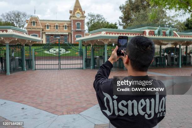 Man takes a photo outside the gates of Disneyland Park on the first day of the closure of Disneyland and Disney California Adventure theme parks as...