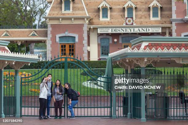 People stand outside the gates of Disneyland Park on the first day of the closure of Disneyland and Disney California Adventure theme parks as fear...