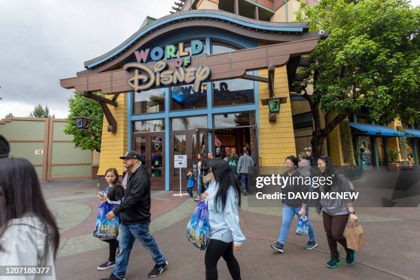 People walk near the World of Disney store in Downtown Disney District shopping mall, which remains open on the first day of the closure of...