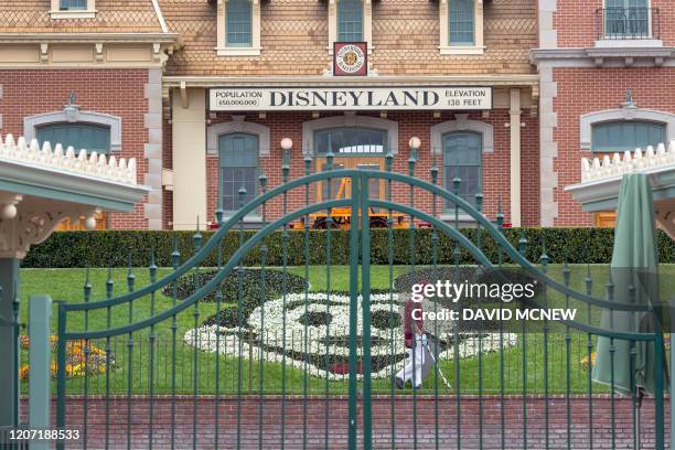 An employee cleans the grounds behind the closed gates of Disneyland Park on the first day of the closure of Disneyland and Disney California...
