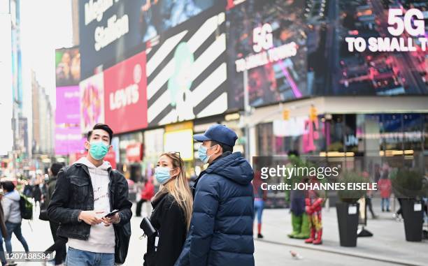 People wearing masks enjoy the sun at Times Square on March 14, 2020 in New York City. - The World Health Organization said March 13, 2020 it was not...