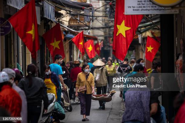 People wear face masks amid concerns of the spread of the COVID-19 Coronavirus while shopping at a local market on March 15, 2020 in Hanoi, Vietnam....