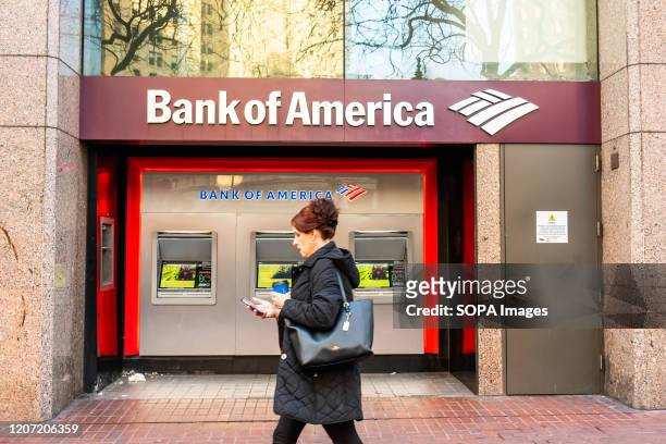Pedestrian walks past Bank of America ATMs.