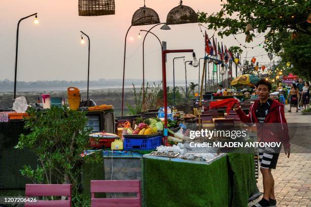 This photograph taken on March 12, 2020 shows an employee inviting customers at an open air restaurant on the banks of the Mekong river in Vientiane.