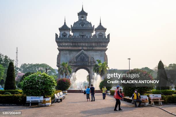 This photograph taken on March 12, 2020 shows people walking in front of the Patuxai war monument in the centre of Vientiane.