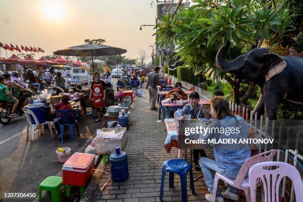 This photograph taken on March 12, 2020 shows people eating street food in Vientiane.