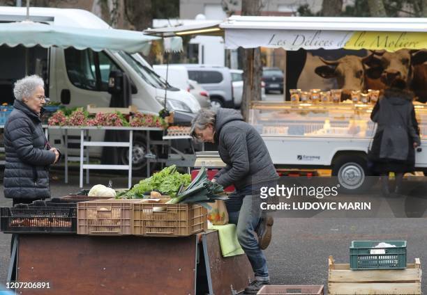 Customers shop for food items at a local market in Cucq, western France on March 15 as France battles the coronavirus that causes the COVID-19...