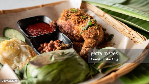 pandan leaf wrapped coconut rice nasi lemak with chicken leg, vegetables and fried egg - nasi lemak stock-fotos und bilder