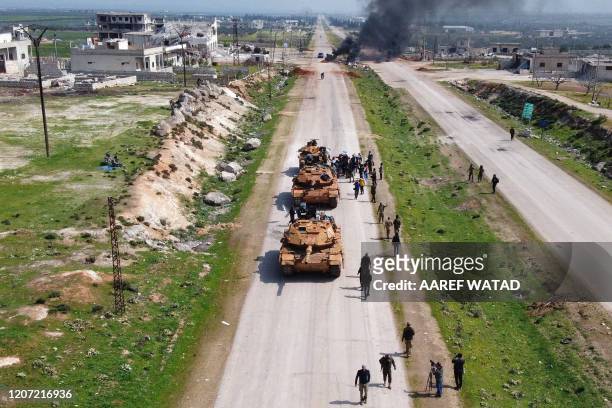 Syrians in protest surround a Turkish military M60T tank as they attempt to block traffic on the M4 highway, which links the northern Syrian...