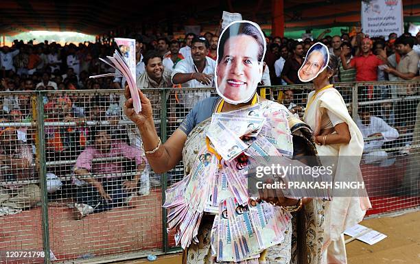 Bharatiya Janata Party Youth Wing activist, wearing a mask bearing the portrait of Congress President Sonia Gandhi, poses with fake currency notes...