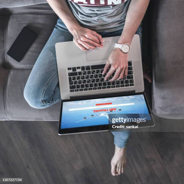 young woman looking for airline tickets on laptop - landing page stock pictures, royalty-free photos & images