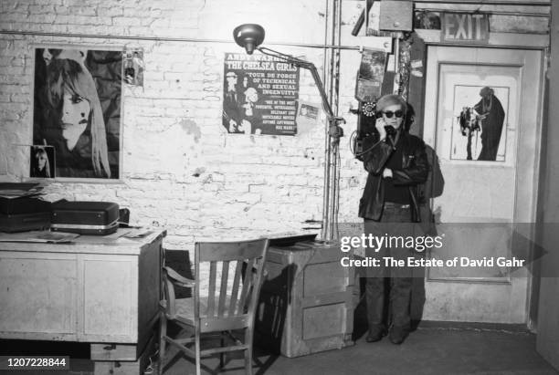 Artist and filmmaker Andy Warhol poses for a portrait in 1966 while making a phone call at a payphone installed in his studio, The Factory , at 231...