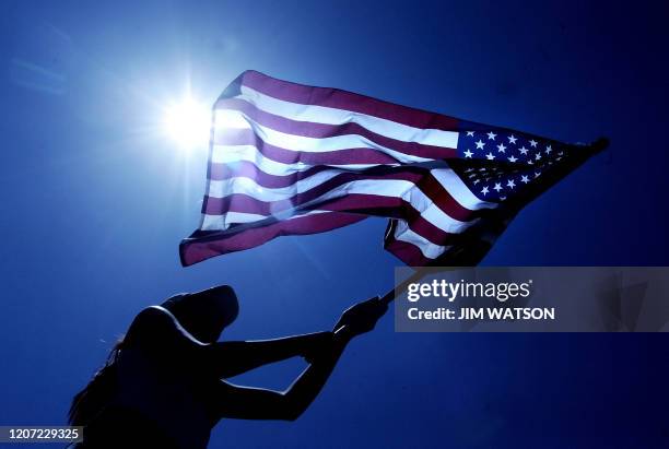 Demonstrator Nallely Vasques, a 16-year-old who left school to participate, waves an American flag as hundreds gather to protest at Malcolm X Park on...