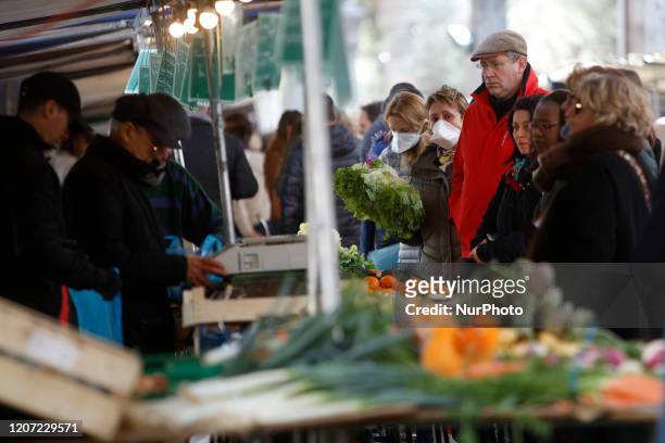 Customers shop for food items at a local market in Paris, France on March 15 as France battles the coronavirus that causes the COVID-19 disease....