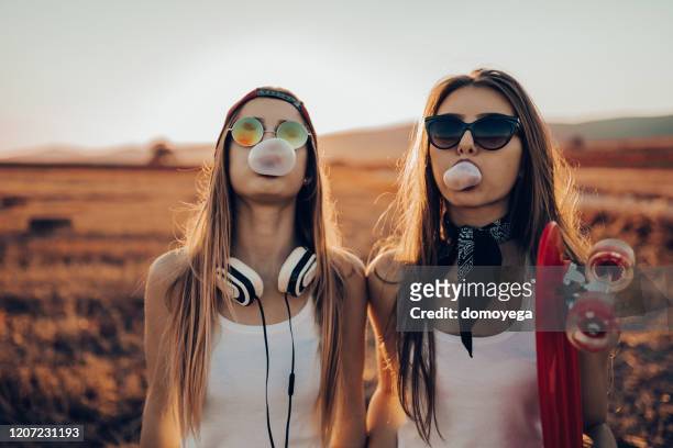 due ragazze adolescenti in stile street che fanno palloncini di gomma da masticare - musica pop foto e immagini stock