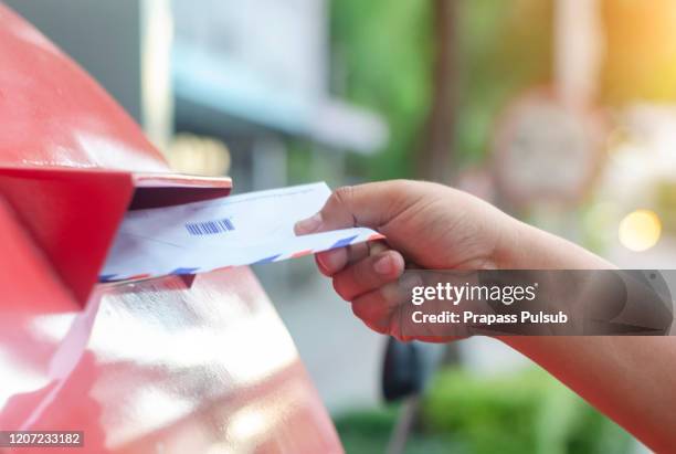 posting a letter to red british postbox on street - correspondencia fotografías e imágenes de stock
