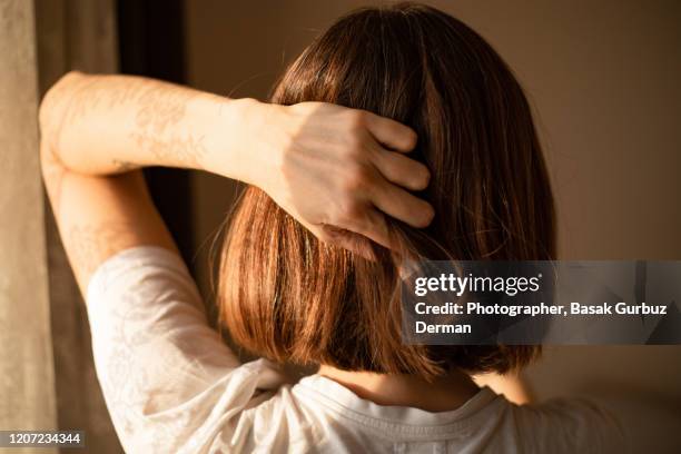 rear view of a woman with bob haircut, holding her head. - bob fotografías e imágenes de stock