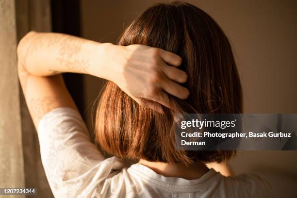 rear view of a woman with bob haircut, holding her head. - short bob haircuts stock pictures, royalty-free photos & images