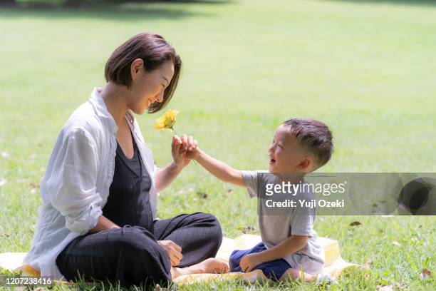 pregnant woman and son relaxing in the park - gift japan photos et images de collection