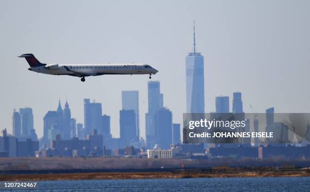 Plane from Delta airline is seen above the skyline of Manhattan before it lands at JFK airport on March 15, 2020 in New York City. - Chaos gripped...